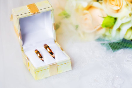 wedding rings in box with bouquet