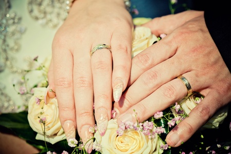 hands of bride and groom with wedding bouquetの写真素材