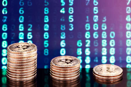 three piles of bitcoins with numbers in backgroundsの写真素材