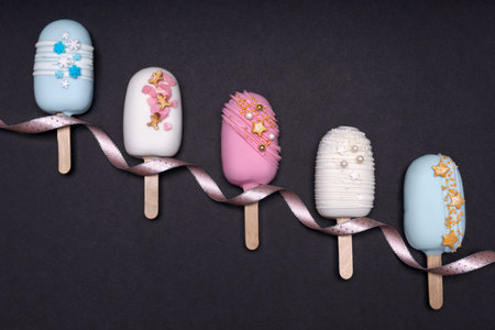 top view of decorated cake pops ice creams on black background
