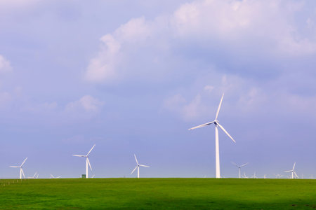 Wind turbine on the green grass over the blue clouded skyのeditorial素材