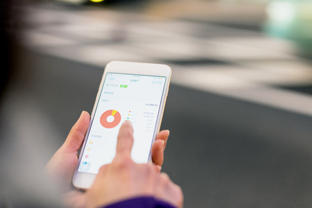 woman checks stock market in mobile phoneのeditorial素材