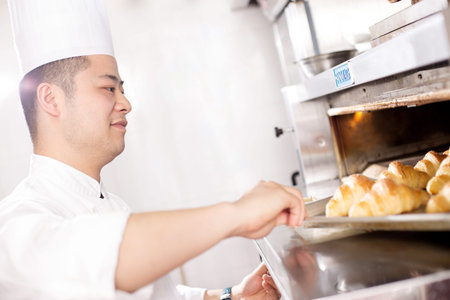 young chinese man chef making bread in kitchen