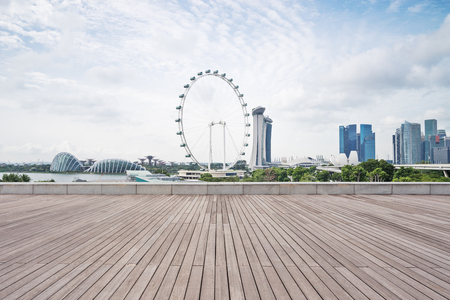 empty wooden sidewalk with modern buildings near ferris wheelのeditorial素材