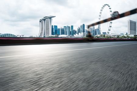 blurry empty asphalt road with road sign and cityscape of singapore in blue cloud skyのeditorial素材