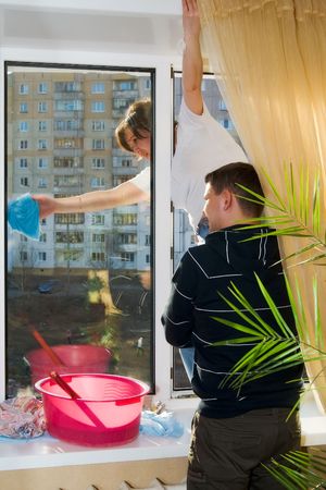 A man and woman wash a window in a houseの写真素材