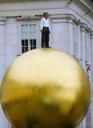 SALZBURG, AUSTRIA  - SEPTEMBER 1: Modern statue  at Kapitelplatz at the historical center of Salzburg  on September 1, 2012. Sculpture of a golden sphere, called Sphaera, with a human figure standing on top, created by sculptor Stephan Balkenhol in 2007のeditorial素材