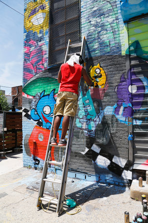 NEW YORK - JUNE 1  Street artist painting mural at Williamsburg in Brooklyn on June 1, 2014  Outdoor art gallery known as the Bushwick Collective has most diverse collection of street art in Brooklyn のeditorial素材