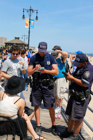 BROOKLYN, NY- JUNE 15 NYPD officers writing ticket for alcohol-related offense at Coney Island Boardwalk  in Brooklyn on June 15, 2014  The NYPD established in 1845, is the largest police force in USAのeditorial素材