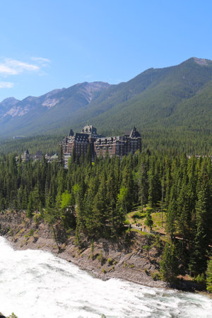 BANFF, CANADA - JULY 28: Banff Springs Hotel in with Bow River Falls in the foreground on July 28, 2014.  The Banff Springs Hotel was built during the 19th century in Scottish Baronial styleのeditorial素材
