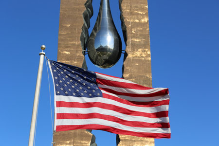 BAYONNE, NEW JERSEY - NOVEMBER 18: American flag in the front of  September 11 memorial To the Struggle Against World Terrorism by Russian artist Zurab Tsereteli on November 18, 2014 in Bayonne.のeditorial素材