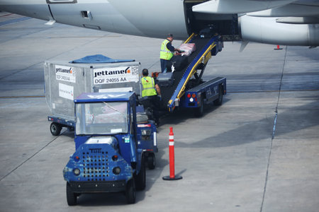 MIAMI, FLORIDA - JUNE 1, 2016: American Airlines baggage handlers uploading luggage at Miami International Airport. American Airlines operates 274 flights every day from Miamiのeditorial素材