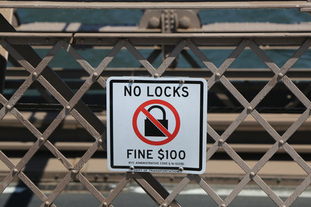 BROOKLYN, NEW YORK - AUGUST 13, 2017: Sign on the Brooklyn Bridge warning people of a $100 fine if you place a lock on the bridgeのeditorial素材