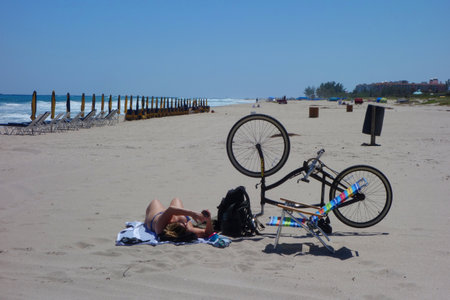 RIVIERA BEACH, FLORIDA - MARCH 21, 2018: Beach goer with bicycle at Singer Island, Fl. Singer Island an oceanfront neighborhood part of the city of Riviera Beach with natural beaches and upscale hotelsのeditorial素材