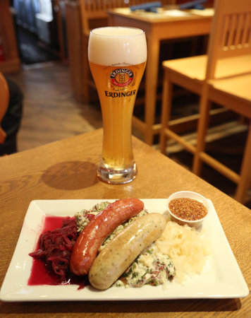NEW YORK - MAY 3, 2018: A glass of German wheat beer Erdinger hefeweizen and sausage plate served in New York's restaurantのeditorial素材