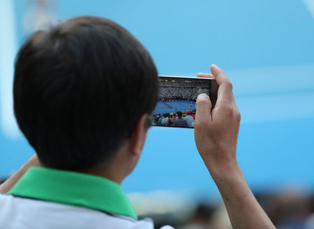 MELBOURNE, AUSTRALIA - JANUARY 24, 2019: Unidentified spectator uses his cell phone to take images...