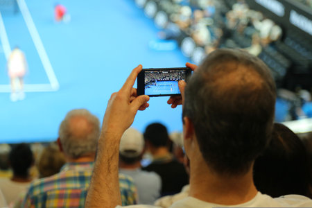 MELBOURNE, AUSTRALIA - JANUARY 27, 2019: Unidentified spectator uses his cell phone to take images during tennis match at 2019 Australian Open in Melbourne Parkのeditorial素材