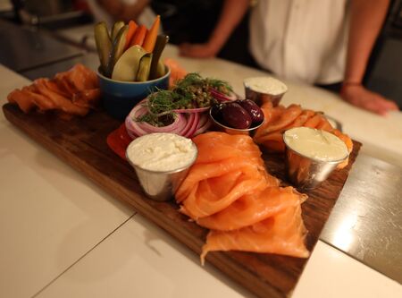 Smoked salmon variety board with cream cheese, tomato, onion , capers and picklesの写真素材