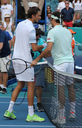 MIAMI GARDENS, FLORIDA - MARCH 27, 2019: Grand Slam champion Roger Federer of Switzerland (R) embraces Daniil Medvedev at the net following his win in the  round of 16 match at 2019 Miami Openのeditorial素材