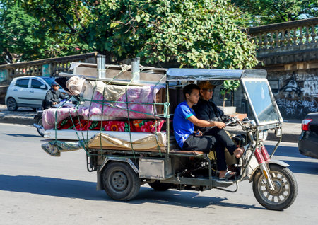 HANOI, VIETNAM - OCTOBER 28, 2019: People on motorbikes bring goods to street market in the Old...