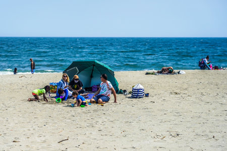 FAR ROCKAWAY, NEW YORK - MAY 15, 2020: Sunbathers and swimmers fill the beach at Rockaway Beach in Jacob Riis Park during COVID-19 pandemic. New York City beaches are currently closed for swimmingのeditorial素材