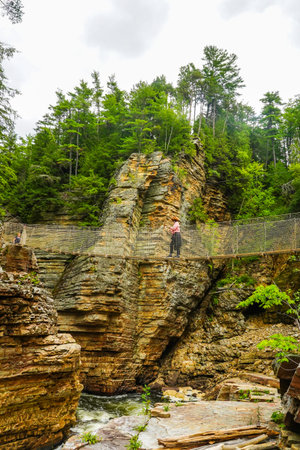 AUSABLE CHASM, NEW YORK - AUGUST 22, 2020: Visitor crossing adventurous rope bridge over Ausable River at Ausable Chasm in Upstate New York. The gorge is about two miles 3.2 km longのeditorial素材