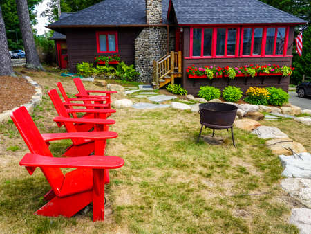 LAKE PLACID, NEW YORK - AUGUST 20, 2020: Red Adirondack Chairs on a Lake Shoreのeditorial素材