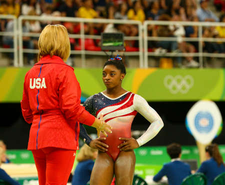 RIO DE JANEIRO, BRAZIL - AUGUST 9, 2016: Olympic champion Simone Biles of United States with coach during team women's all-around gymnastics competition at Rio 2016 Olympic Games at Rio Olympic Arenaのeditorial素材