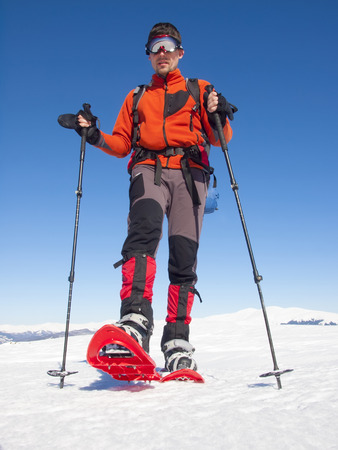 The man in snowshoes and with trekking poles is in the mountains.の写真素材