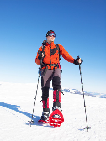 The man in snowshoes and with trekking poles is in the mountains.の写真素材