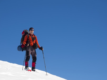 The man in snowshoes and with trekking poles is in the mountains.の写真素材