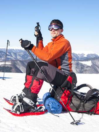 The man in snowshoes and with trekking poles is in the mountains.の写真素材