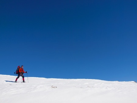 The man in snowshoes and with trekking poles is in the mountains.の写真素材