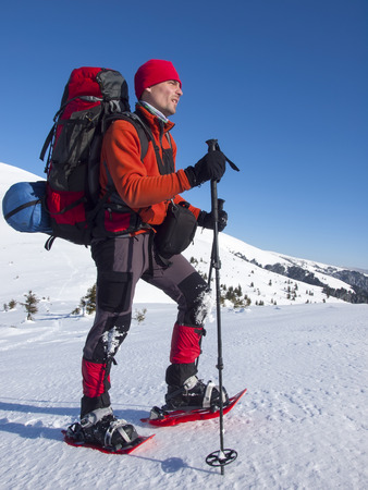 The man in snowshoes and with trekking poles is in the mountains.の写真素材