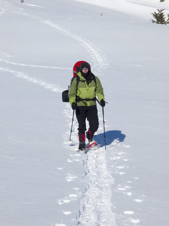 The man in snowshoes and with trekking poles is in the mountains.の写真素材