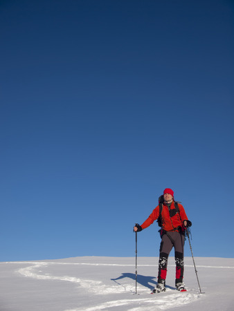 The man in snowshoes and with trekking poles is in the mountains.の写真素材