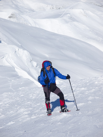 The man in snowshoes and with trekking poles is in the mountains.の写真素材