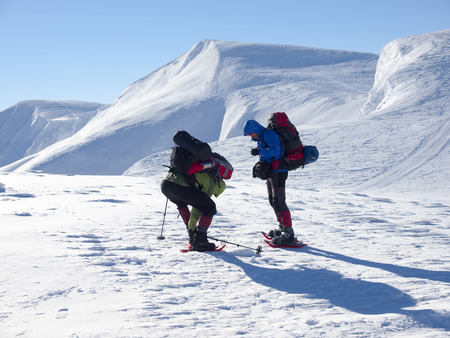 Men in snowshoes and with trekking poles go in the mountains.の写真素材