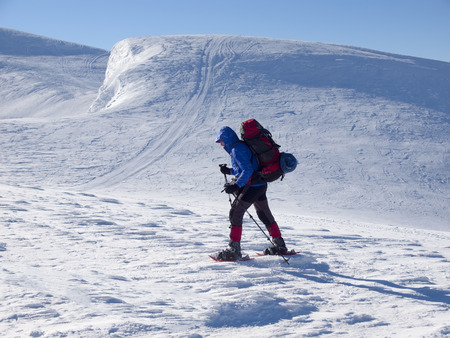 The man in snowshoes and with trekking poles is in the mountains.の写真素材