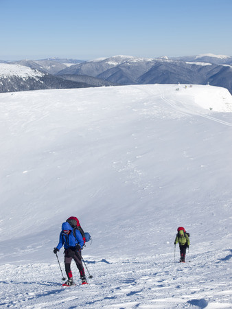 Men in snowshoes and with trekking poles go in the mountains.の写真素材