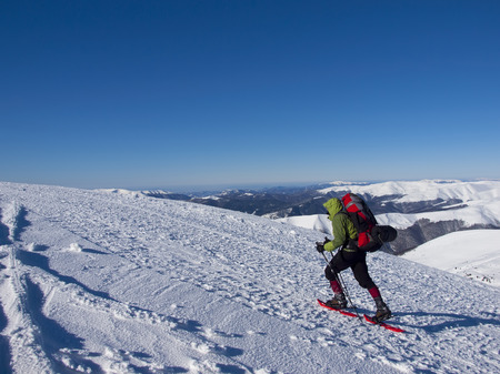 The man in snowshoes and with trekking poles is in the mountains.の写真素材