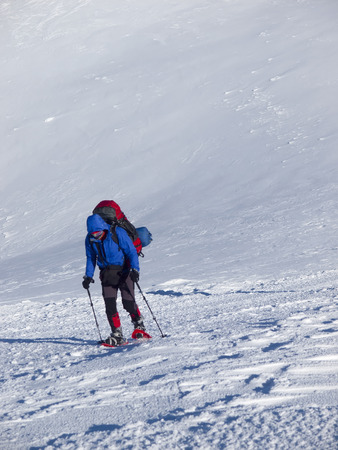 The man in snowshoes and with trekking poles is in the mountains.の写真素材
