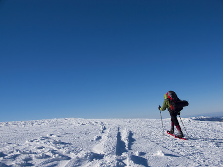 The man in snowshoes and with trekking poles is in the mountains.の写真素材