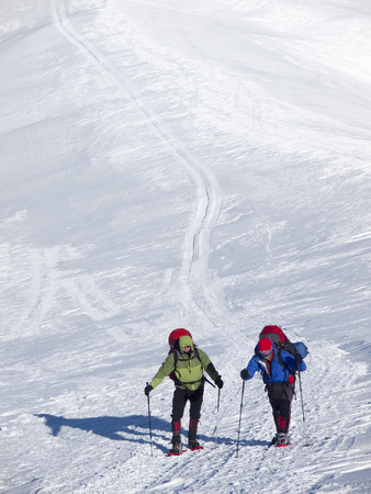 Men in snowshoes and with trekking poles go in the mountains.の写真素材