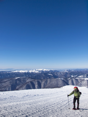 The man in snowshoes and with trekking poles is in the mountains.の写真素材