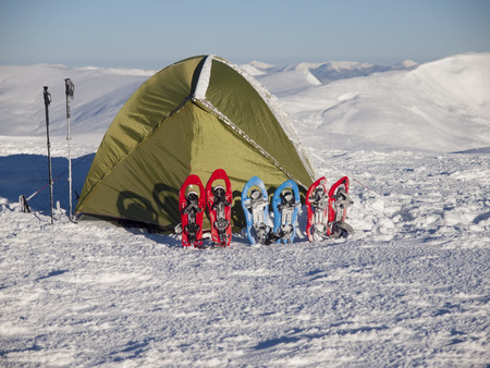 Snowshoes and snow-covered tent on snow in the mountains.の写真素材