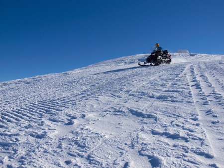 The man riding on the snowmobile from the mountain.の写真素材