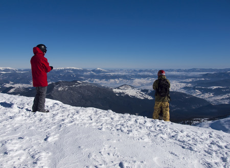 Snowboarders on the background of snow-capped mountains and blue sky.の写真素材