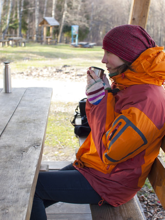 The girl sits at a wooden table and drinking の写真素材