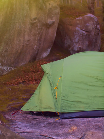 Green tent with equipment costs under rocks.の写真素材